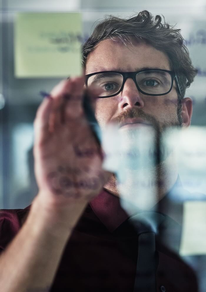 Businessman writing on a glass board 